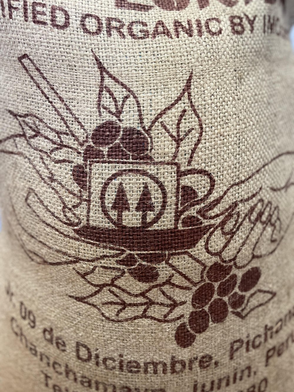 A burlap sack that has a coffee cup and coffee cherries on it